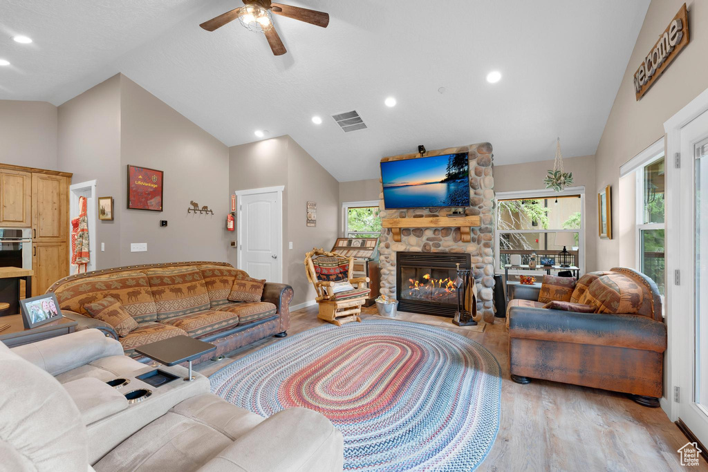 Living area featuring plenty of natural light, light wood-type flooring, a ceiling fan, a stone fireplace, and recessed lighting