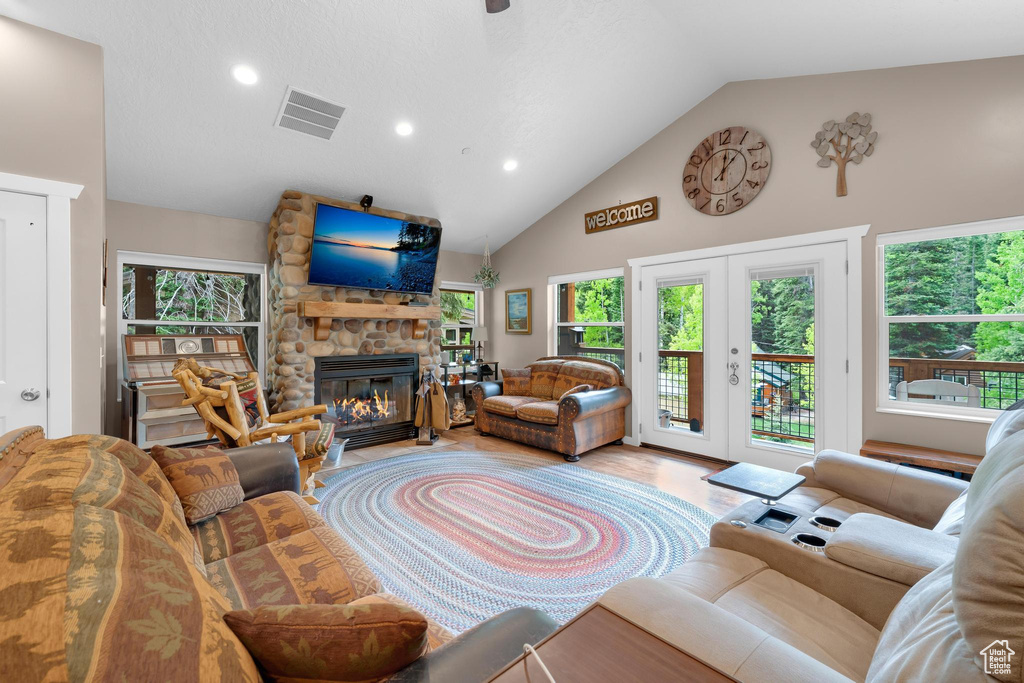 Living room featuring healthy amount of natural light, a fireplace, wood finished floors, recessed lighting, and high vaulted ceiling