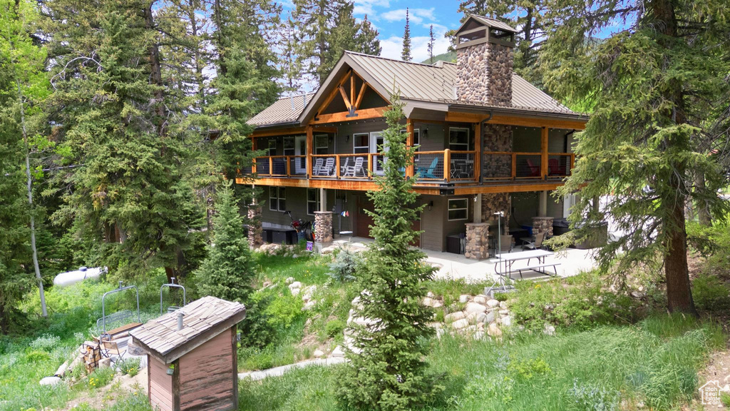 Back of house with stone siding, a patio area, a deck, metal roof, and a standing seam roof