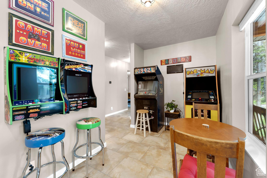 Rec room featuring a textured ceiling, baseboards, and tile patterned flooring