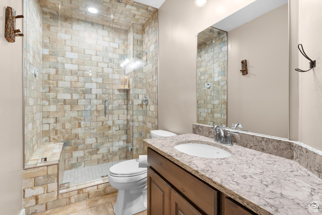 Full bath with toilet, vanity, and a shower stall