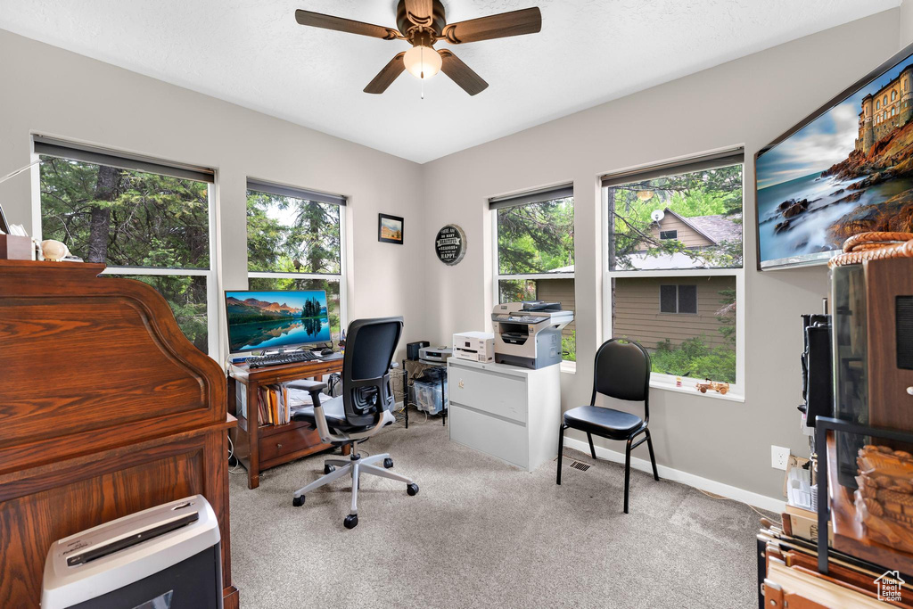 Carpeted office space with ceiling fan and baseboards