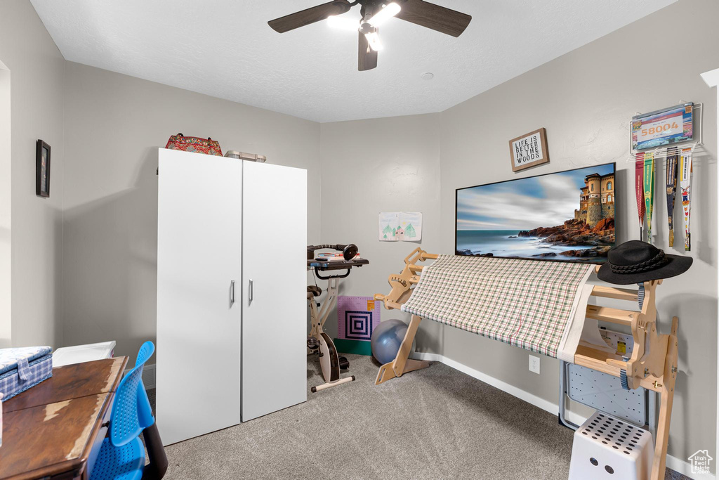 Carpeted home office with ceiling fan and baseboards
