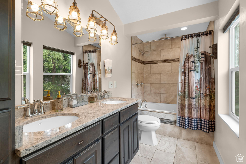 Bathroom with a combined bath / shower with rainfall shower, double vanity, toilet, lofted ceiling, and a chandelier