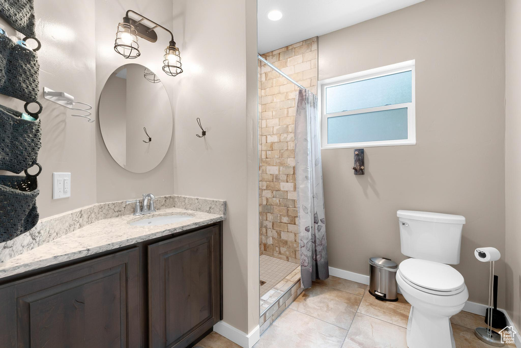 Bathroom featuring vanity, toilet, a stall shower, tile patterned floors, and baseboards