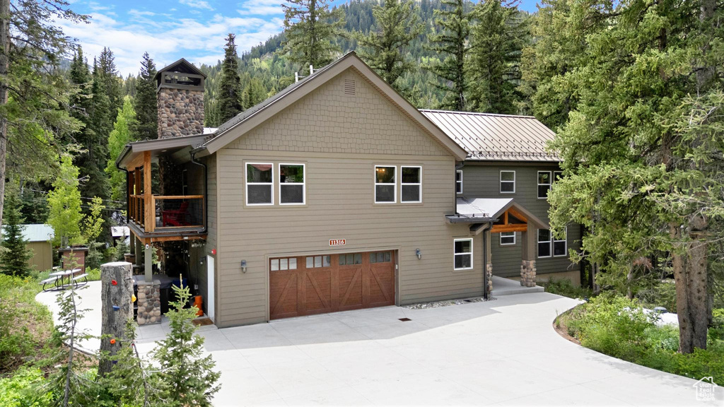 View of front facade featuring concrete driveway, an attached garage, and a chimney