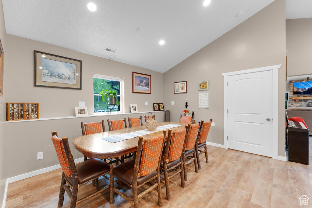 Dining area featuring lofted ceiling, light wood-style flooring, recessed lighting, and baseboards