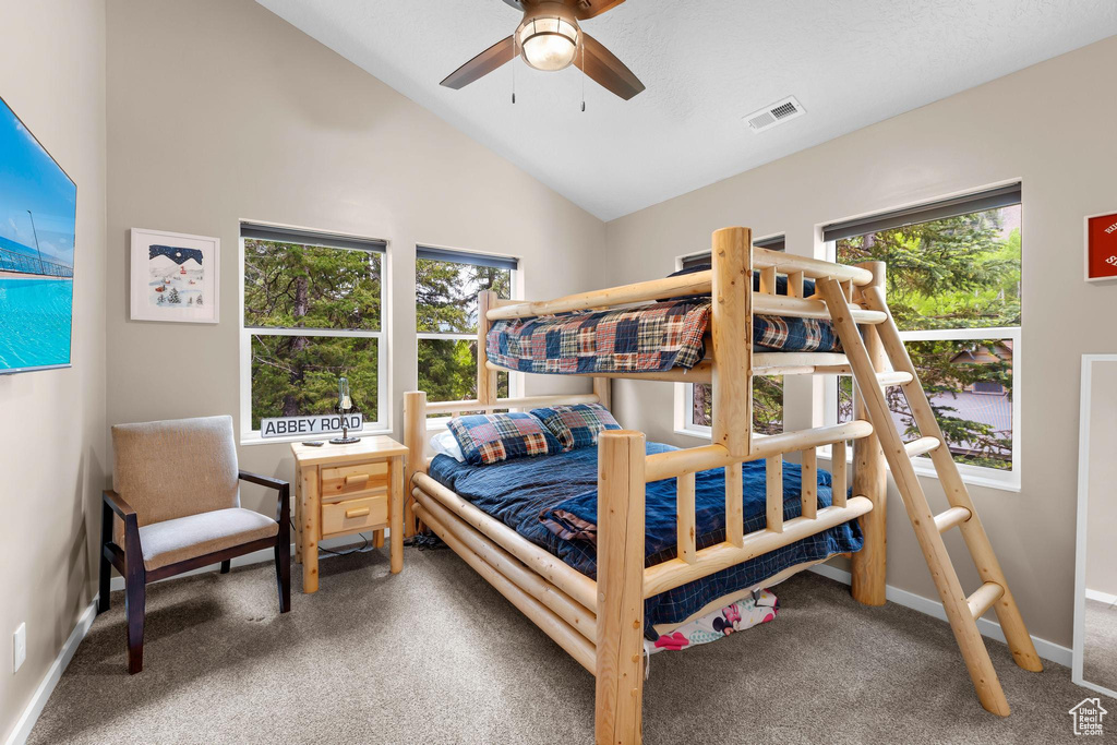 Bedroom featuring carpet flooring, multiple windows, vaulted ceiling, baseboards, and a ceiling fan