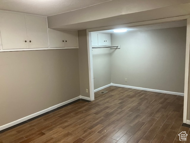 Finished basement with dark wood-style flooring and baseboards
