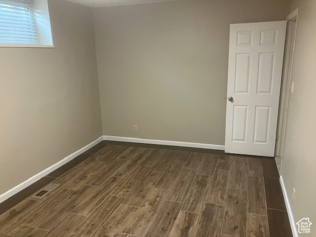 Unfurnished room with dark wood-type flooring and baseboards