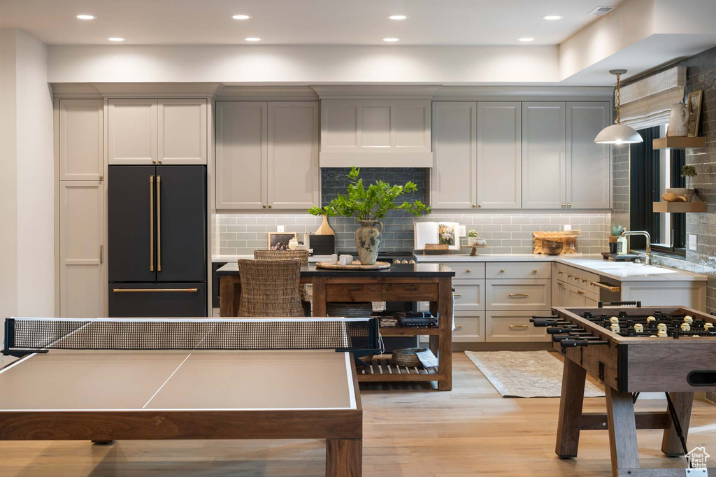 Kitchen with built in refrigerator, light wood finished floors, tasteful backsplash, a sink, and recessed lighting