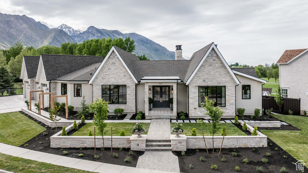 View of front facade with stone siding, a chimney, a garden, and a mountain view