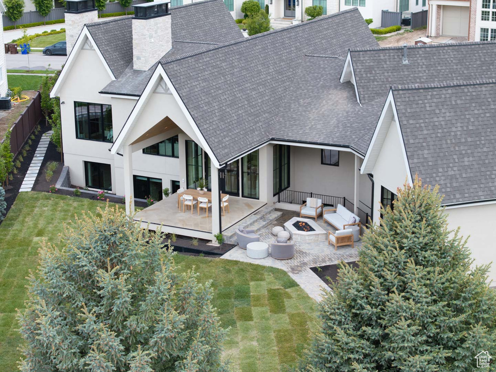 Rear view of house featuring roof with shingles, a chimney, and stucco siding