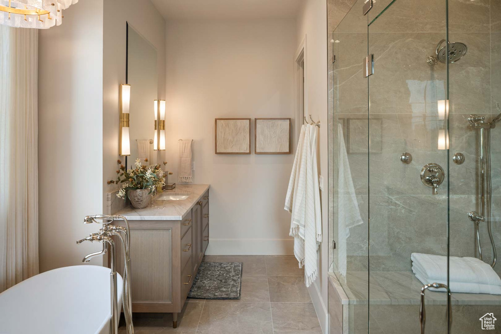 Full bath featuring a soaking tub, vanity, a stall shower, and baseboards