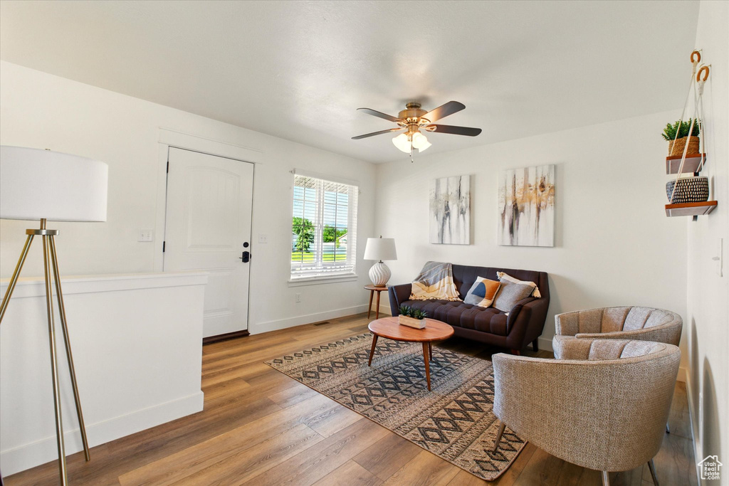 Living area featuring light wood finished floors, a ceiling fan, and baseboards