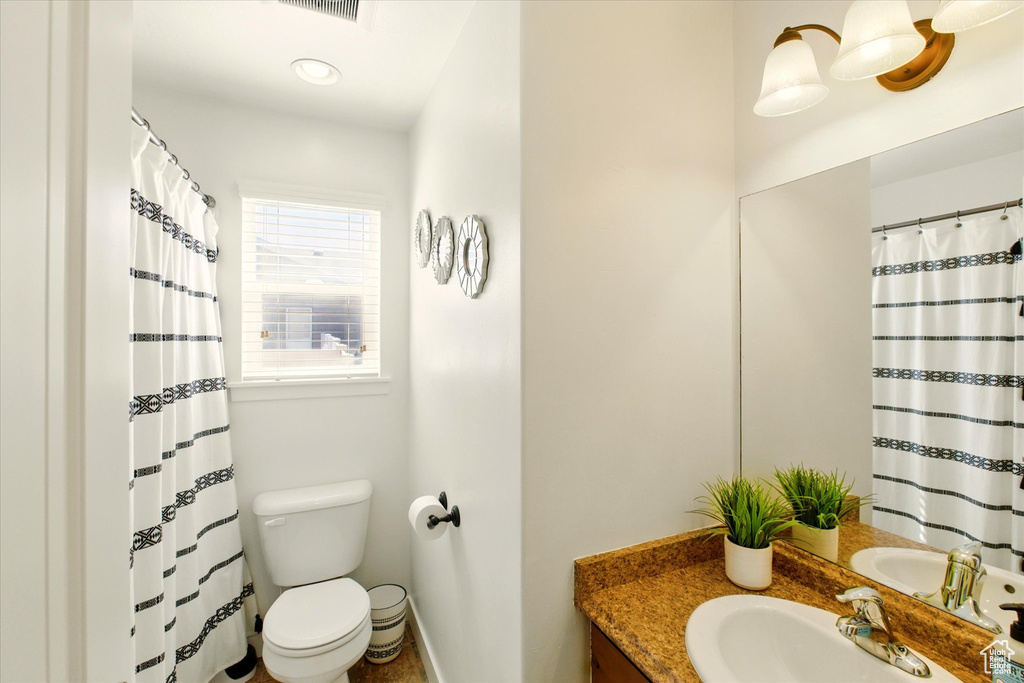 Bathroom featuring toilet, vanity, baseboards, and a shower with shower curtain