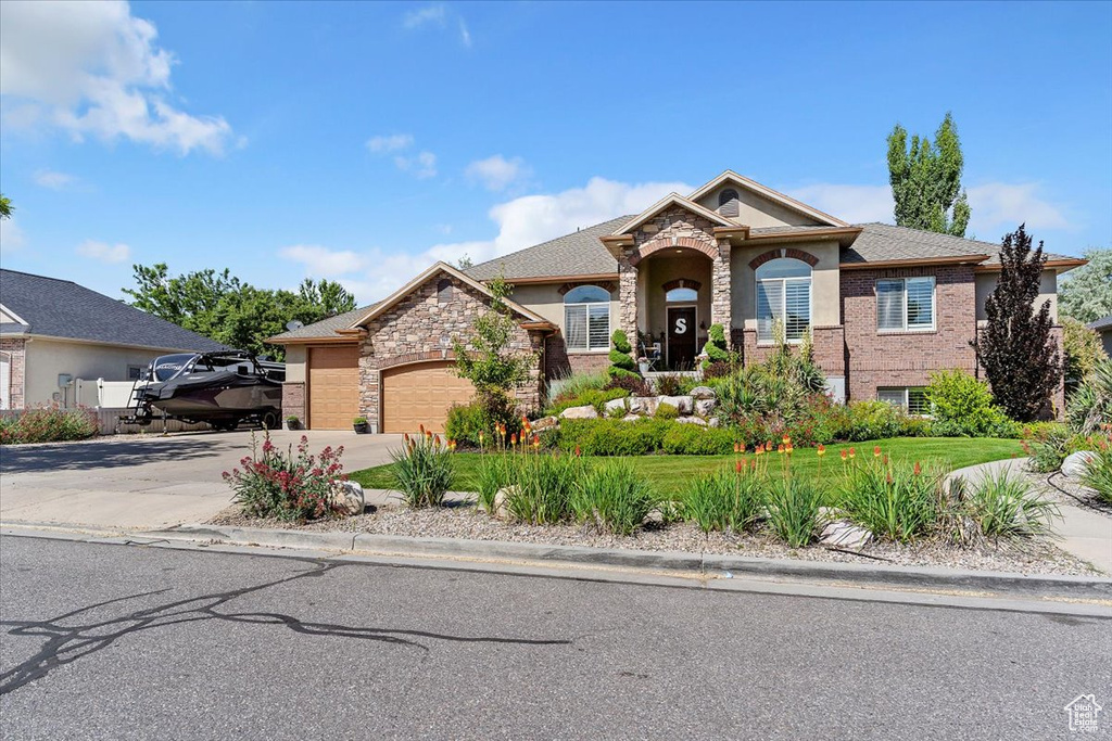 View of front of home featuring an attached garage, concrete driveway, stone siding, and stucco siding