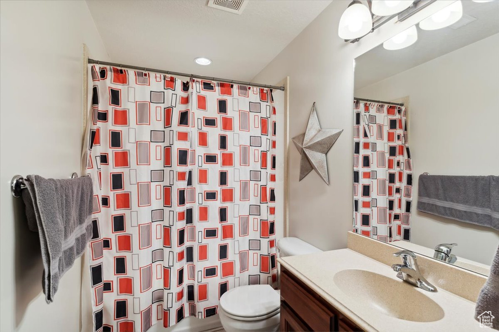 Full bathroom with toilet, vanity, and a shower with shower curtain