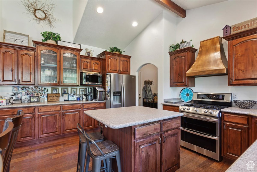 Kitchen with stainless steel appliances, custom exhaust hood, beam ceiling, dark wood-style flooring, and light countertops