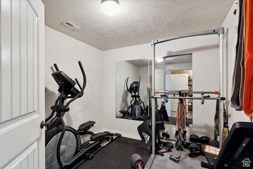 Exercise area with a textured ceiling and baseboards