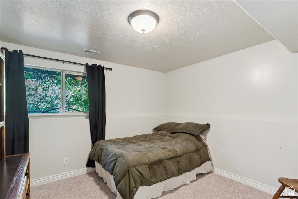 Carpeted bedroom featuring a textured ceiling and baseboards