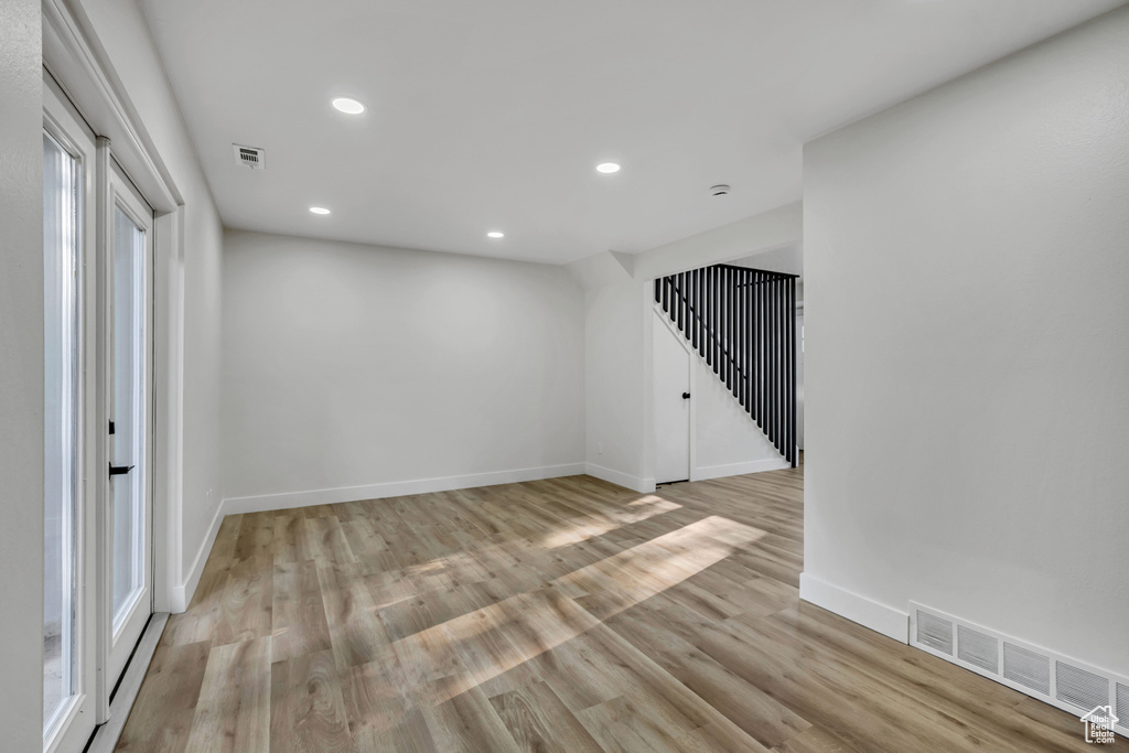 Unfurnished room with recessed lighting, light wood-style flooring, baseboards, and stairs