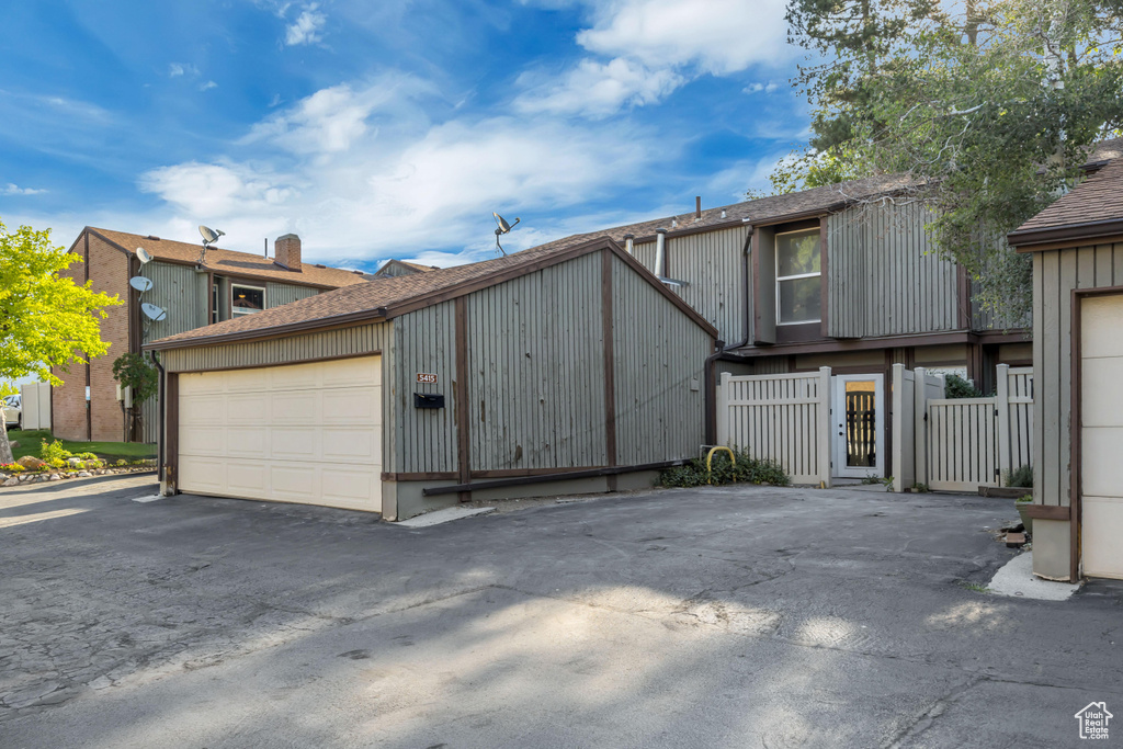 View of side of property featuring a shingled roof and a detached garage