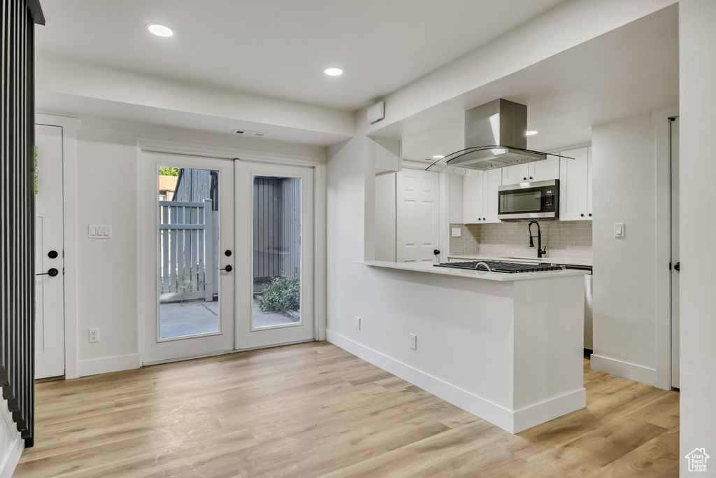 Kitchen with stainless steel microwave, french doors, island range hood, white cabinetry, and recessed lighting