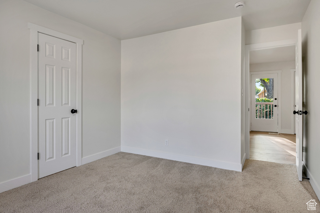 Empty room with light carpet, a smoke detector, and baseboards