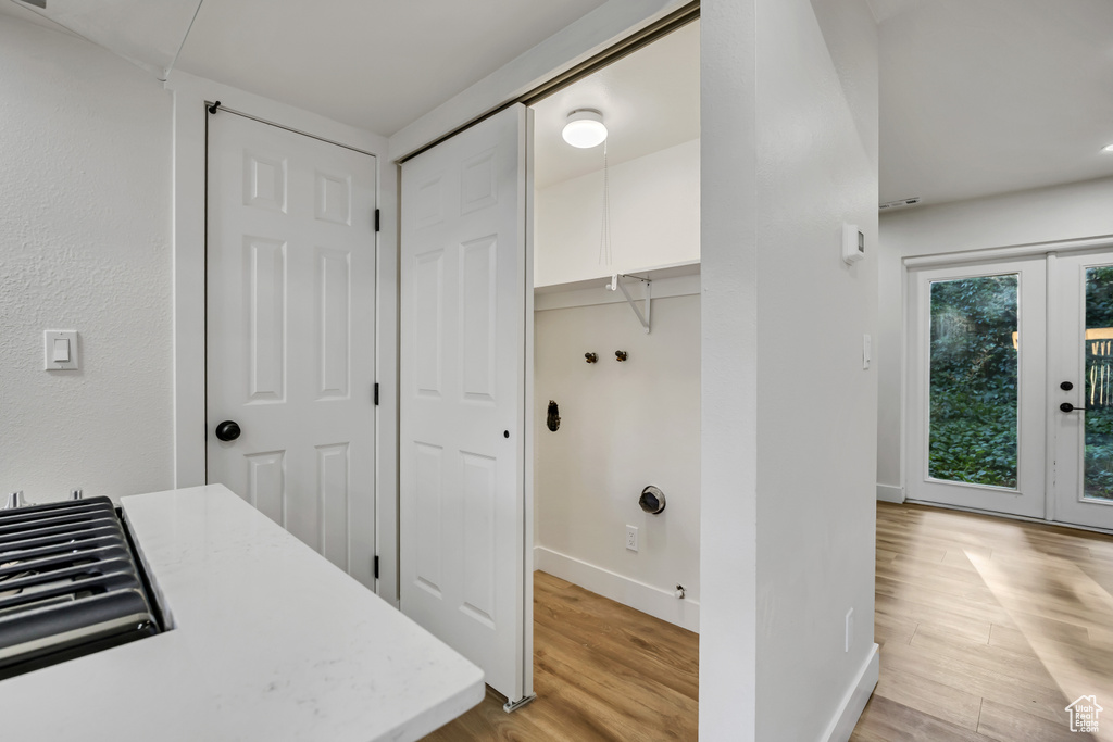 Laundry area featuring washer hookup, baseboards, light wood-style flooring, and french doors