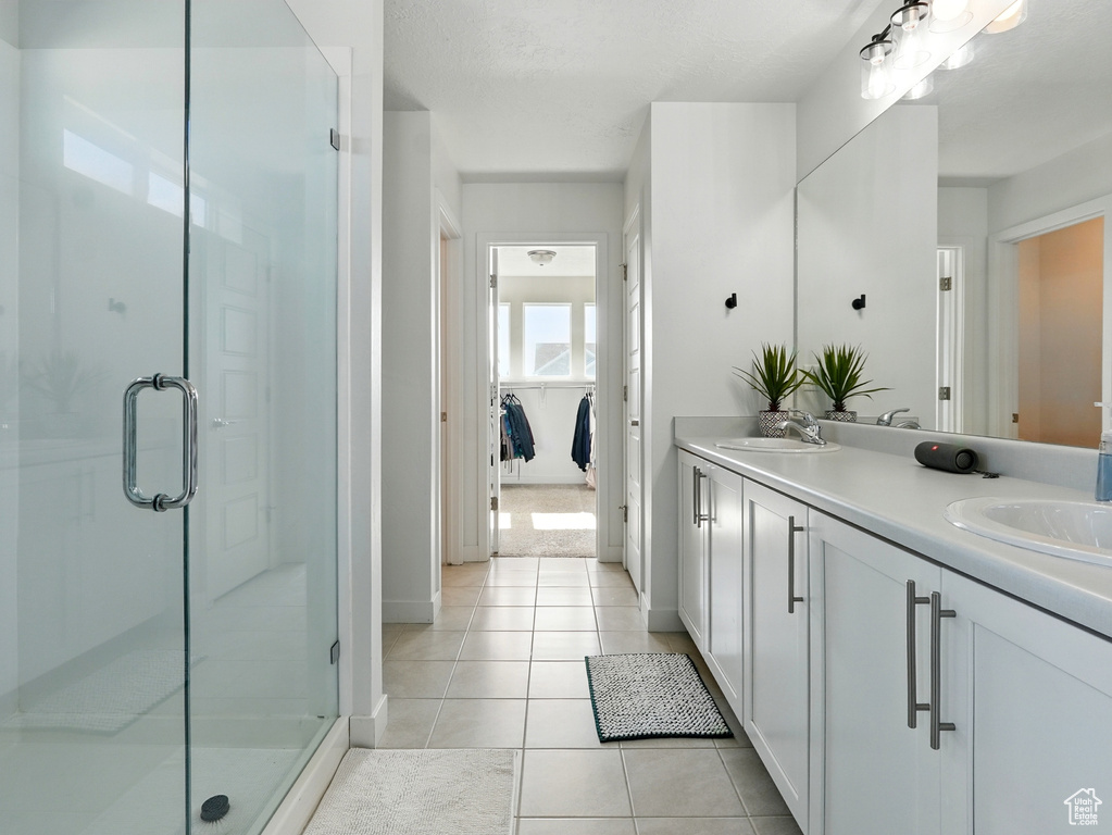 Bathroom featuring double vanity, a stall shower, tile patterned flooring, and baseboards