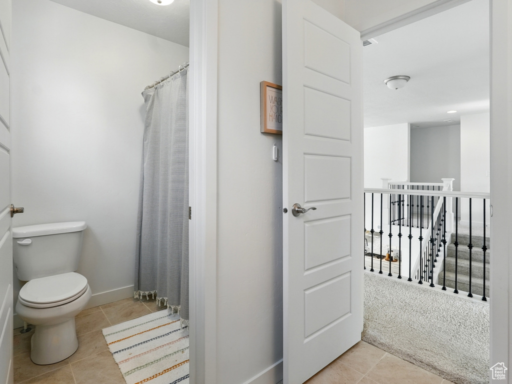 Full bath with tile patterned floors, toilet, baseboards, and a shower with curtain