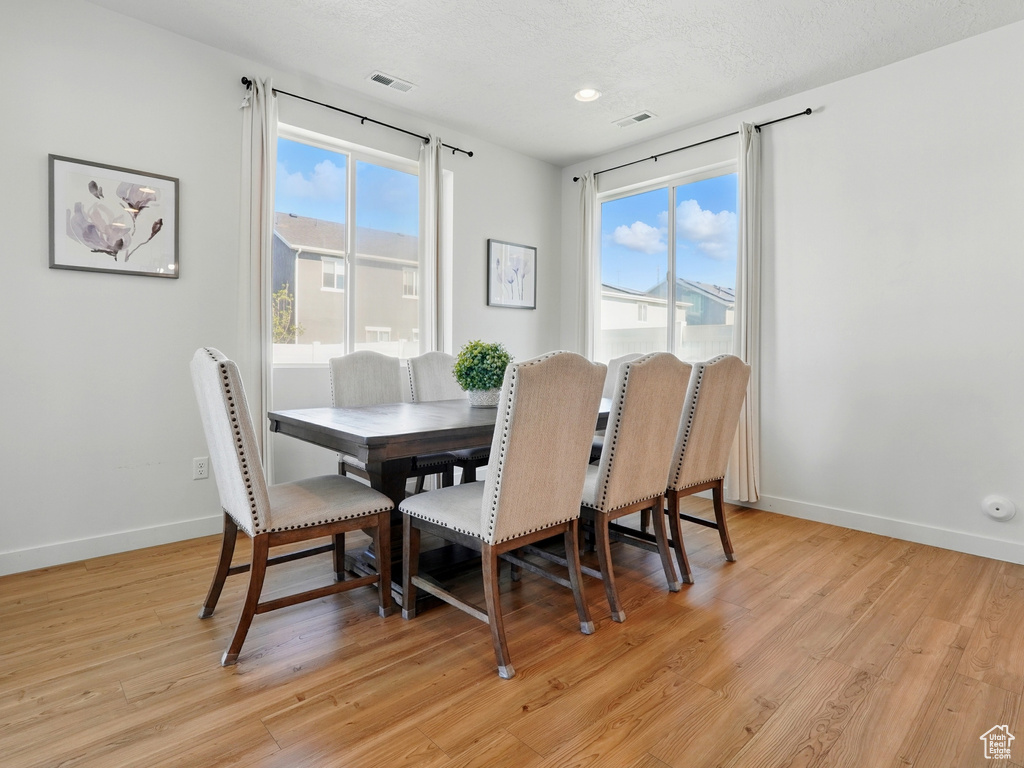 Dining area with plenty of natural light, baseboards, light wood finished floors, recessed lighting, and a textured ceiling