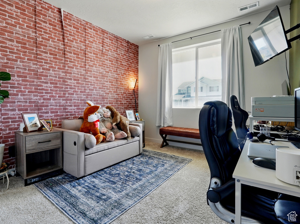 Carpeted office featuring brick wall