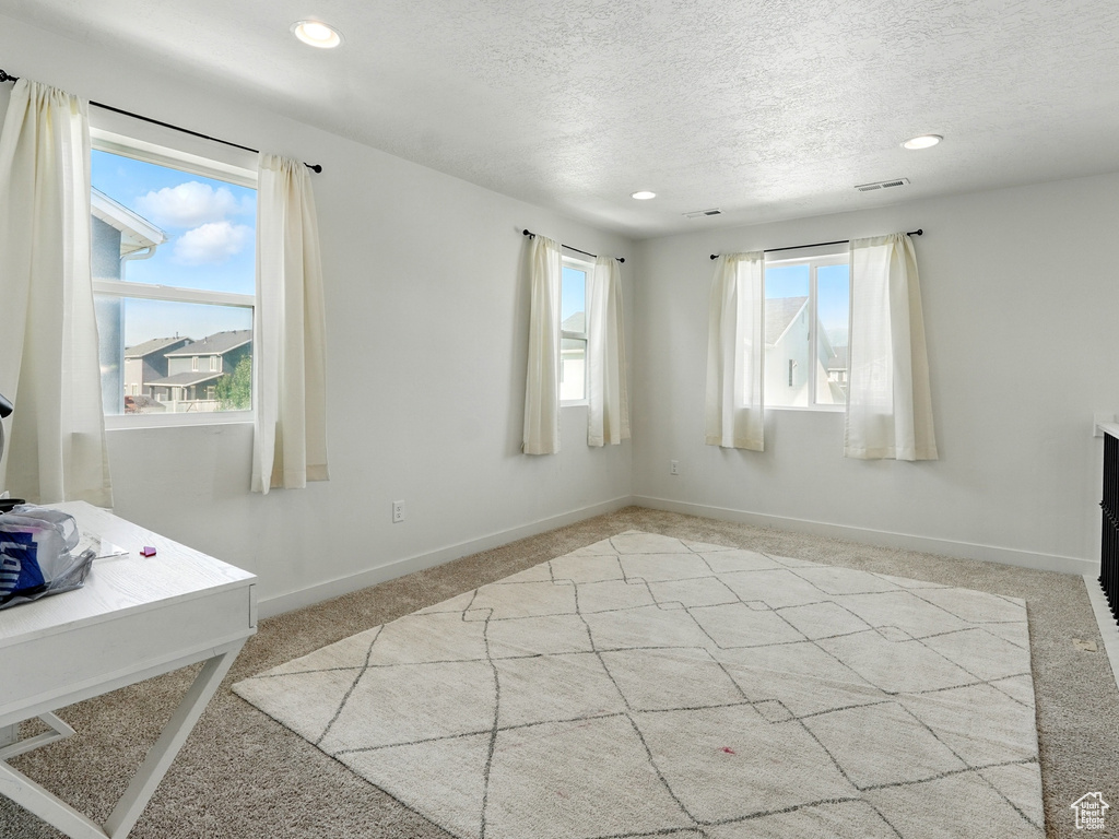 Unfurnished room with light colored carpet, a textured ceiling, recessed lighting, and baseboards