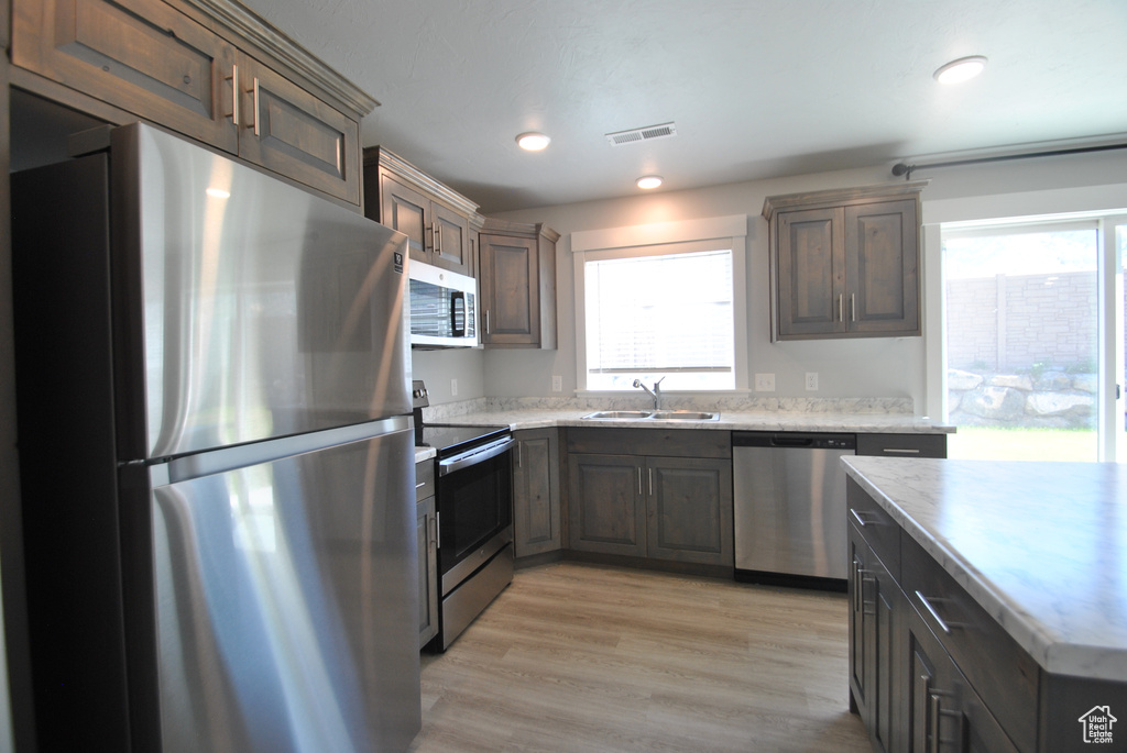 Kitchen featuring appliances with stainless steel finishes, a sink, light wood-type flooring, and recessed lighting