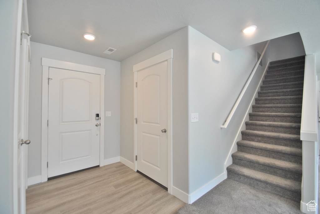 Entrance foyer featuring baseboards, stairway, and light wood finished floors
