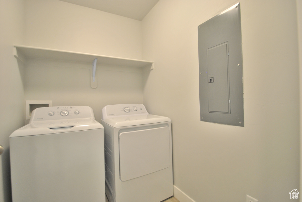 Laundry area with electric panel, independent washer and dryer, and baseboards