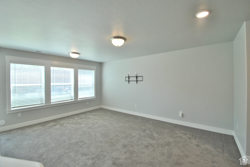 Unfurnished room with dark carpet and baseboards