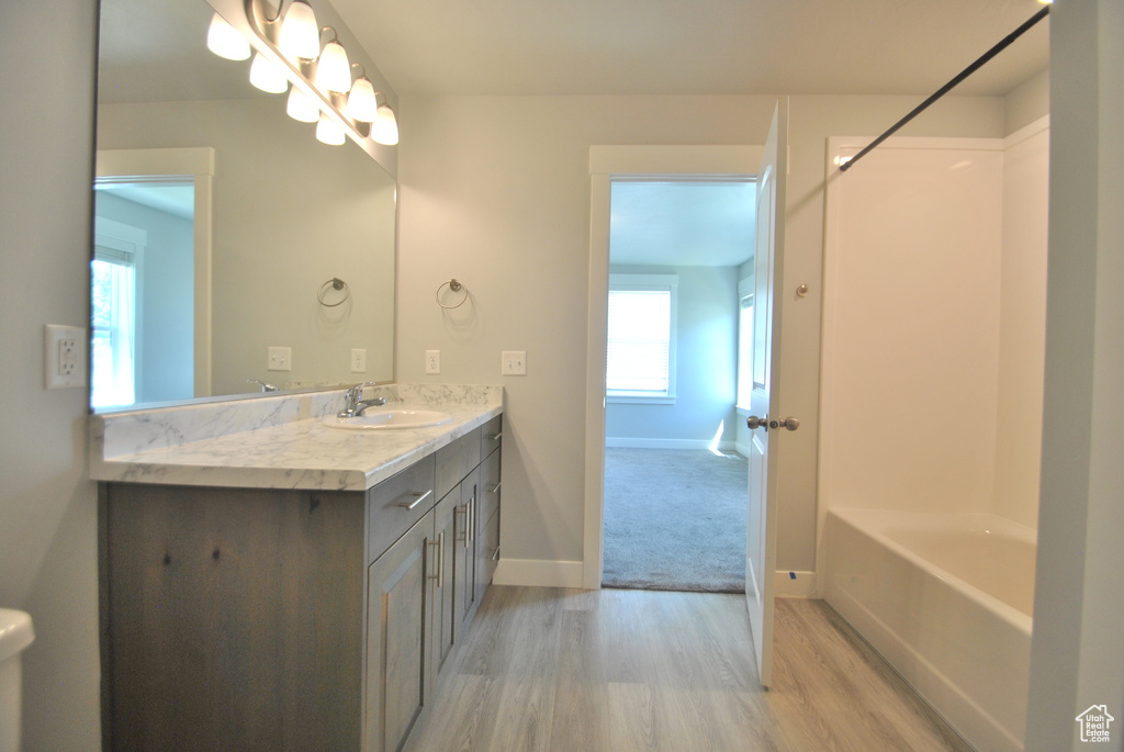 Full bathroom with vanity, wood finished floors, baseboards, and tub / shower combination
