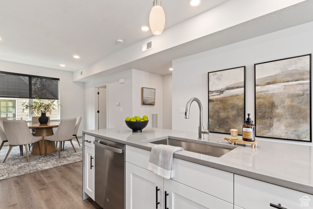 Kitchen with a sink, stainless steel dishwasher, dark wood-type flooring, white cabinets, and recessed lighting