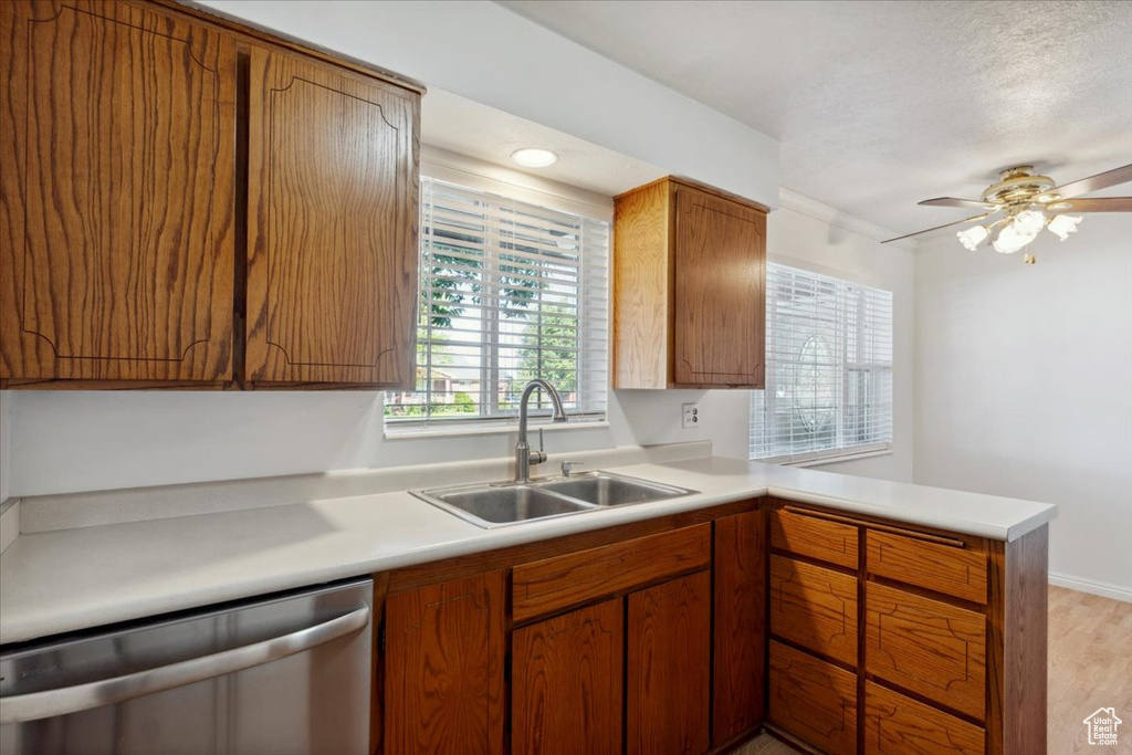 Kitchen featuring stainless steel dishwasher, a sink, a peninsula, light countertops, and ceiling fan