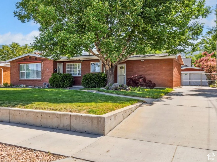 Single story home featuring brick siding, a garage, driveway, and a gate