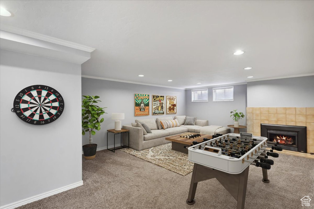 Living area with carpet floors, recessed lighting, crown molding, a tiled fireplace, and baseboards