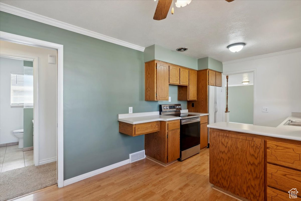 Kitchen featuring stainless steel electric stove, a ceiling fan, light wood finished floors, brown cabinetry, and baseboards