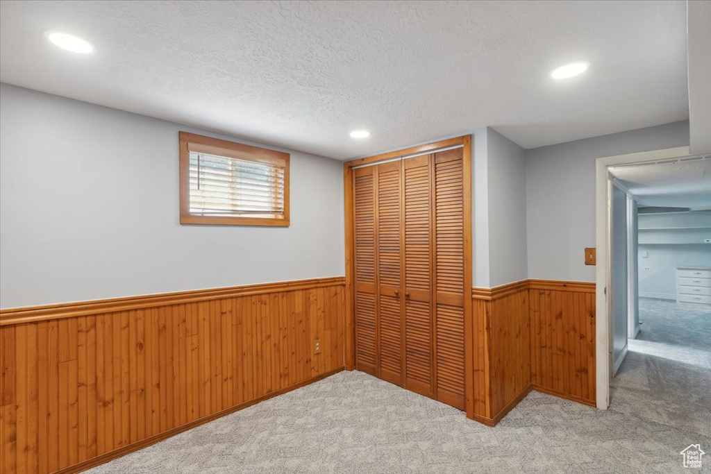 Unfurnished bedroom with wainscoting, a closet, carpet flooring, wooden walls, and recessed lighting
