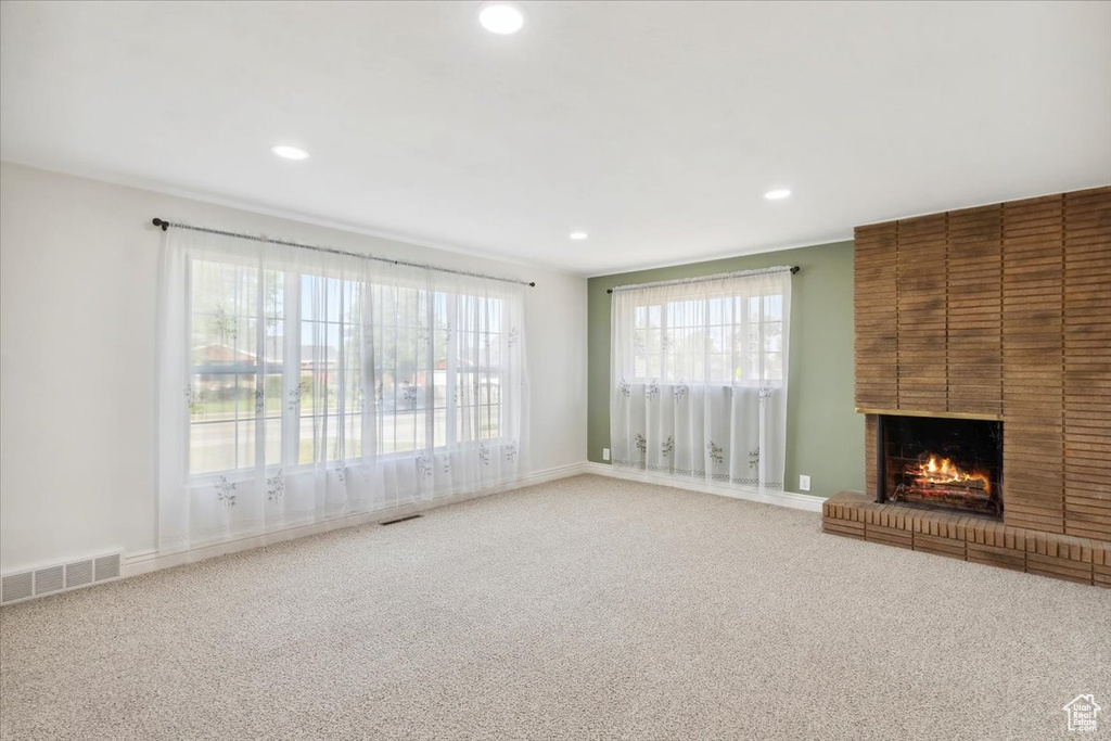 Unfurnished living room featuring carpet floors, recessed lighting, a brick fireplace, and healthy amount of natural light