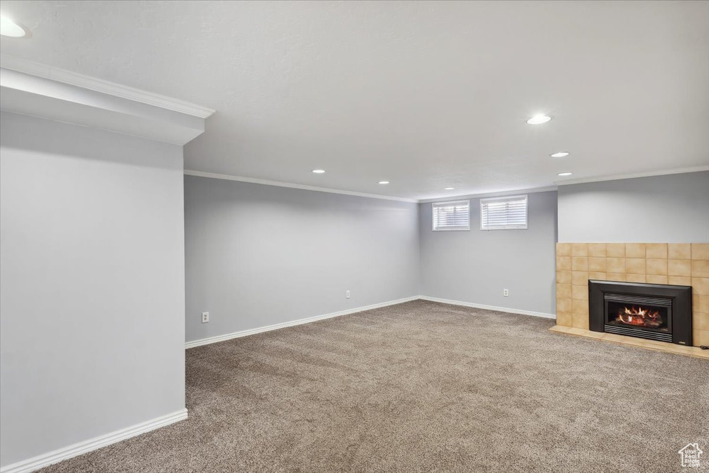 Basement featuring carpet, recessed lighting, a tiled fireplace, ornamental molding, and baseboards