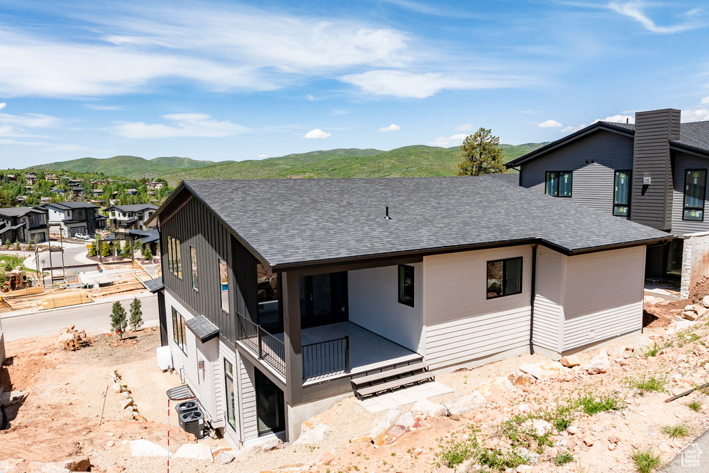 Rear view of property with a shingled roof, a mountain view, and a residential view