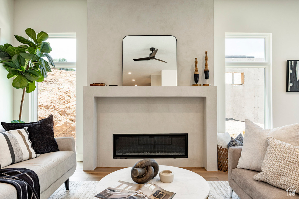 Living room featuring a glass covered fireplace, wood finished floors, and healthy amount of natural light